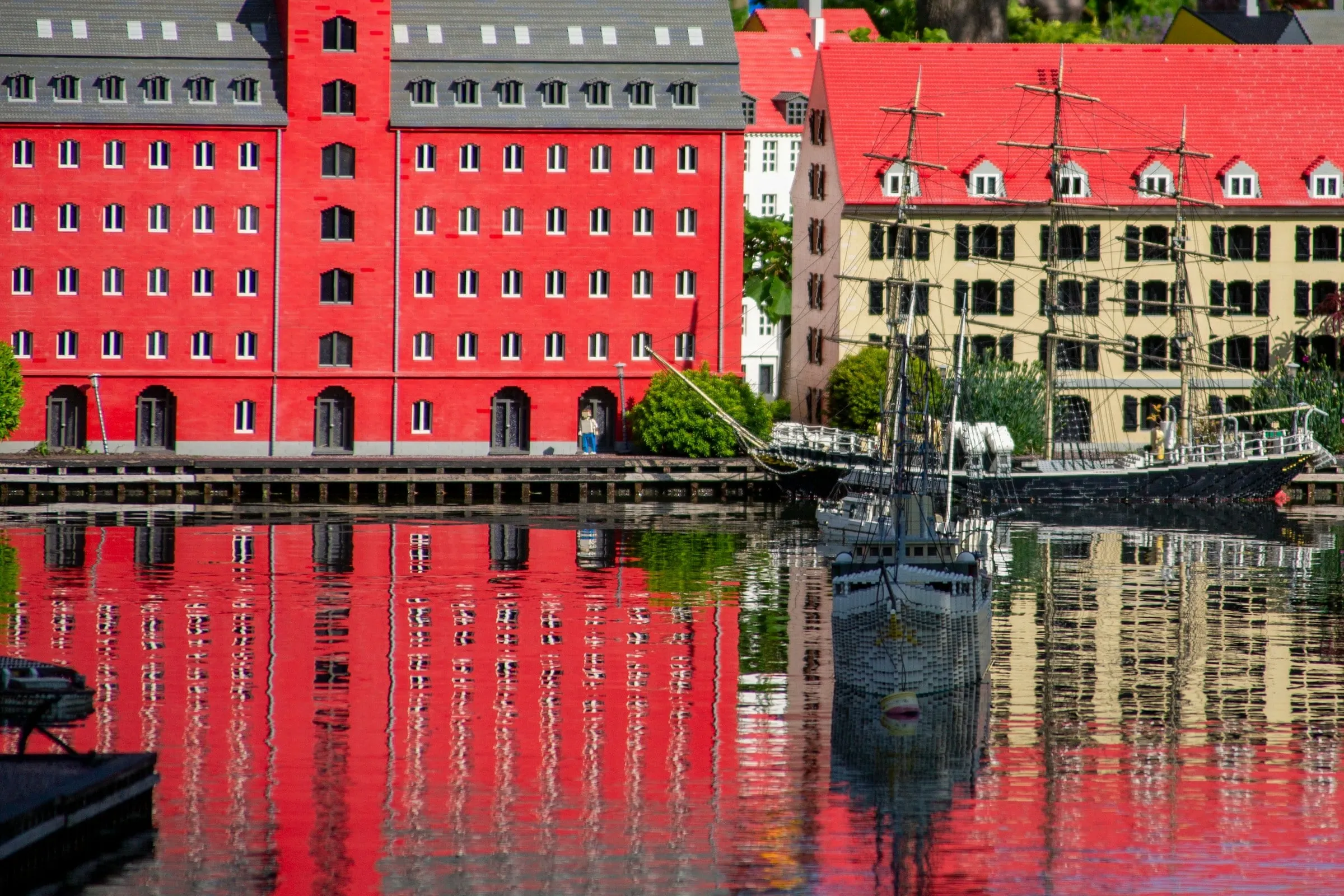Miniland im LEGOLAND Billund: rotes Speicherhaus und Segelschiff aus LEGO-Steinen spiegeln sich im Hafenbecken